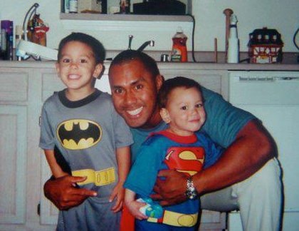 Dad with two young sons dressed as Batman and Superman