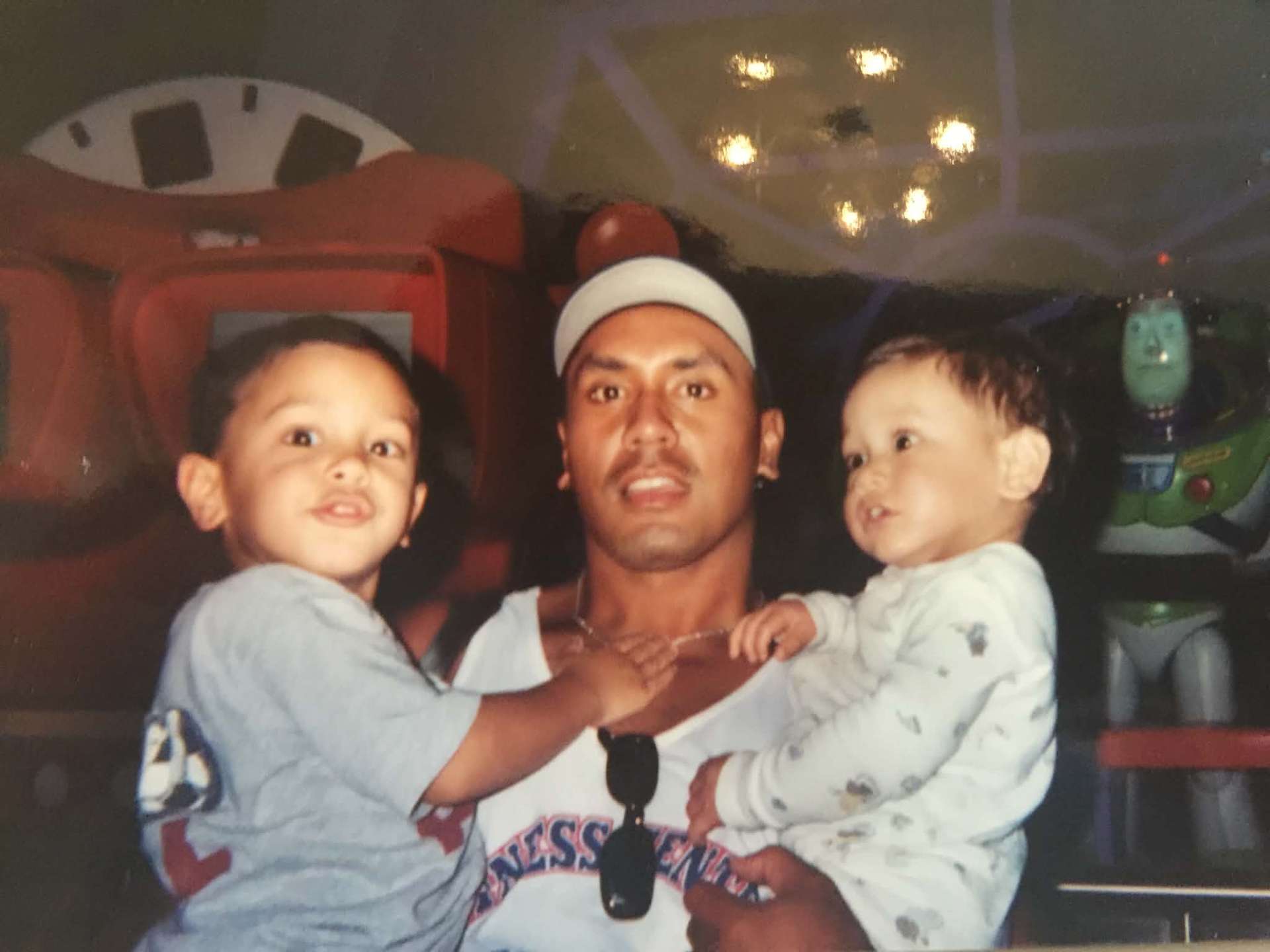 Dad holding two young boys near a Buzz Lightyear display