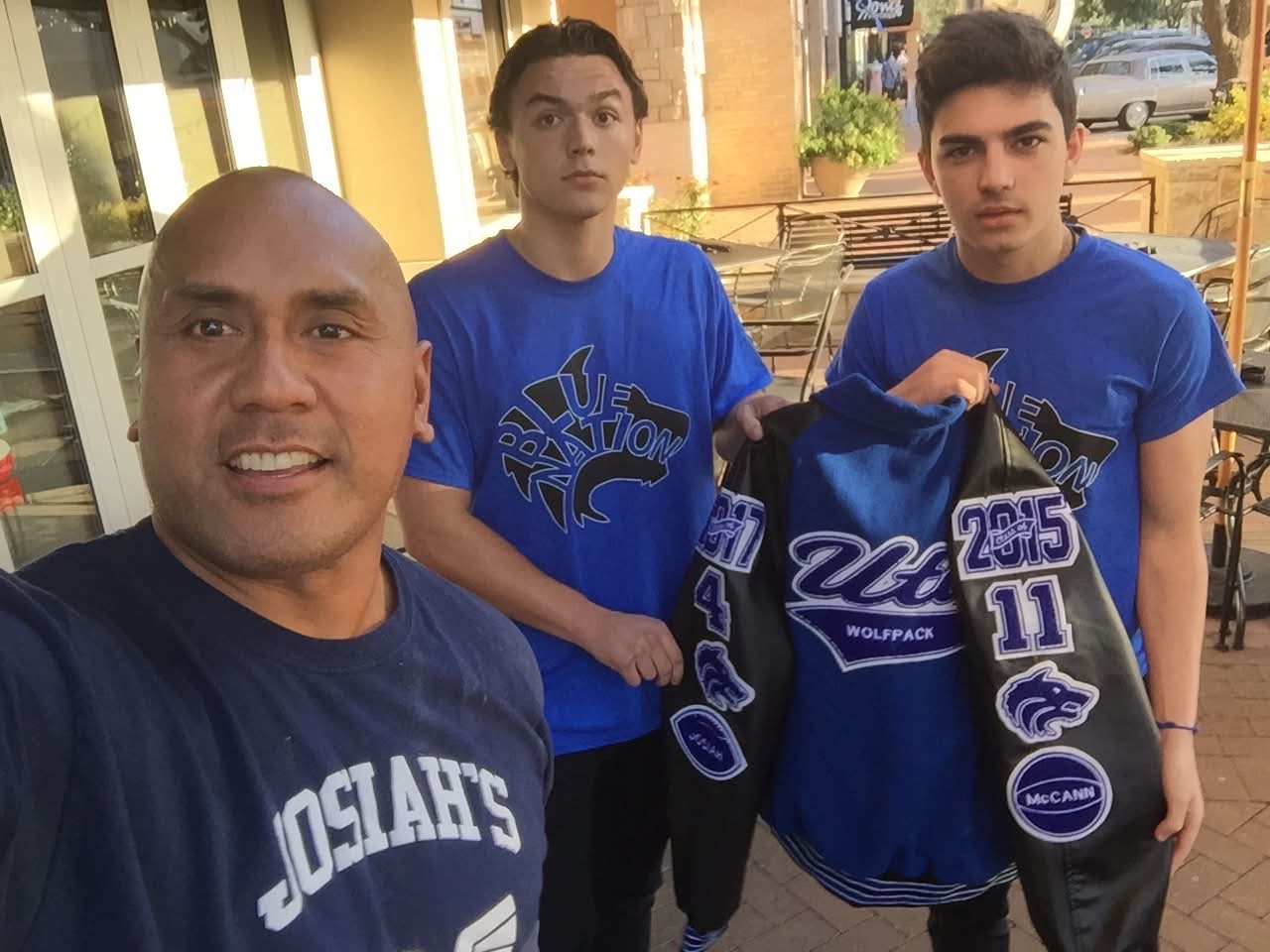 Dad with McCann Jr. and Josiah in Blue Nation shirts holding McCann's letterman jacket